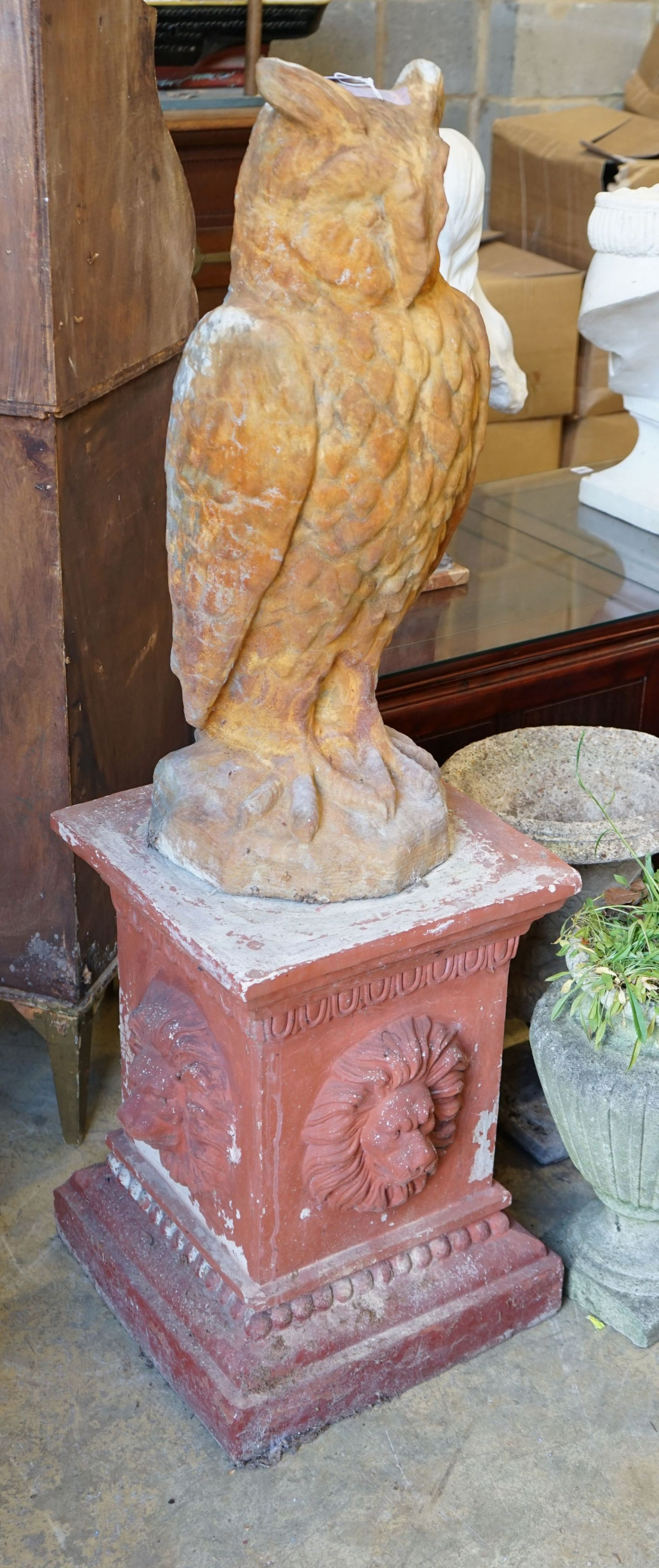 A reconstituted stone owl garden ornament on terracotta plinth, total height 130cm